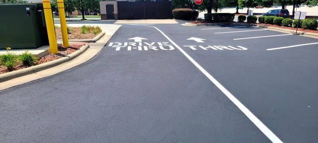 Empty driveway lane with white road markings and a curbside sidewalk near a building entrance