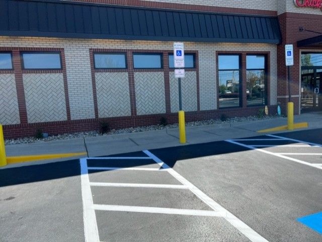 Accessible parking spaces and storefront entrance with yellow bollards in front of a building