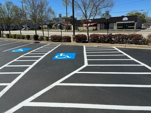 Empty accessible parking spaces with blue wheelchair symbols in a sunny parking lot in Raleigh, NC