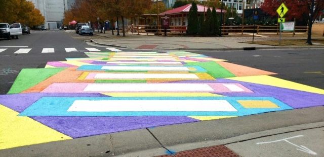 Colorful rainbow crosswalk painted across a street intersection on an overcast day