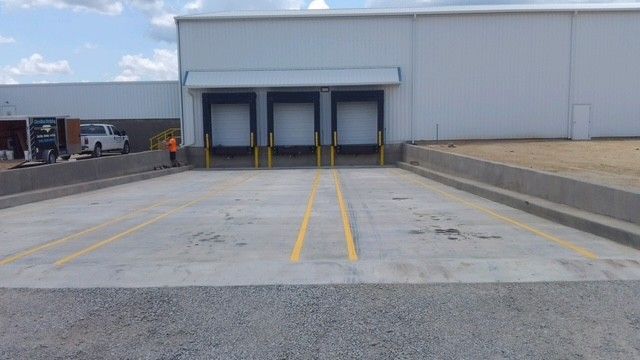 Loading dock with three bay doors and yellow safety lines on a concrete lot