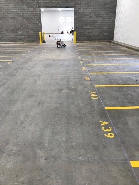 Empty parking garage with yellow bay lines and a person near the far wall