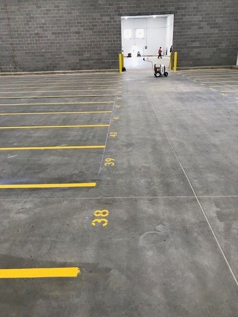 Empty warehouse loading area with yellow-striped parking spaces and two scooters near a bright doorway