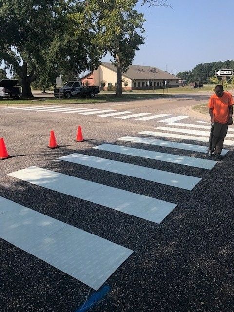 Temporary crosswalk painted on a street with orange cones and a worker nearby.