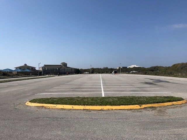 Empty parking lot with yellow curb and grassy median under a clear blue sky