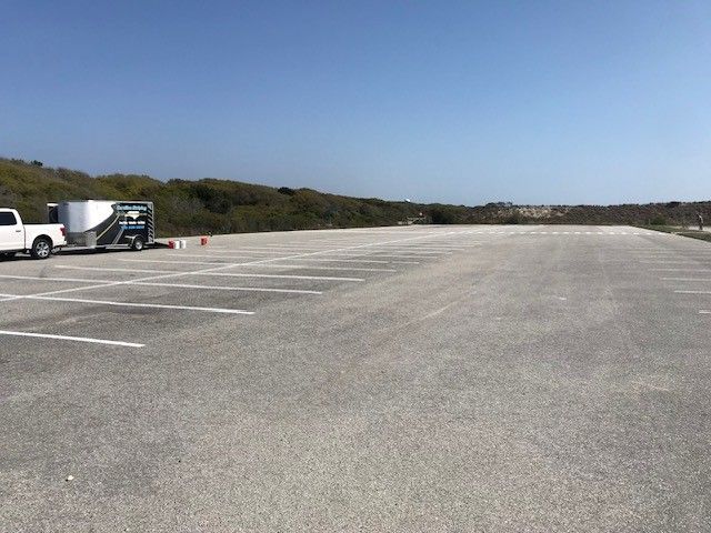 Empty parking lot with a truck and trailer on the left under a clear blue sky