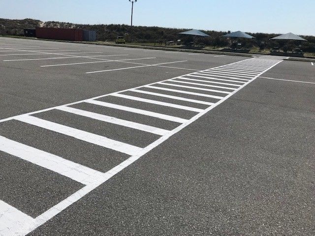 Diagonal white striped line across an empty gray parking lot under a clear sky in Raleigh, NC