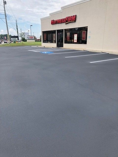 Empty asphalt parking lot outside a store entrance with red signage on a beige building