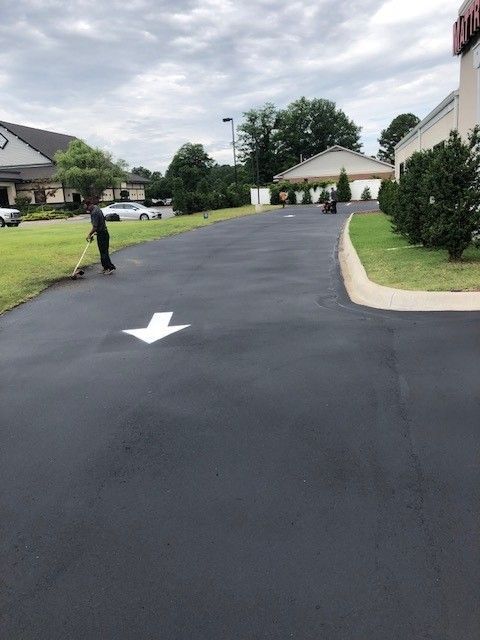 Freshly paved suburban street with white directional arrow and a person standing at the left side