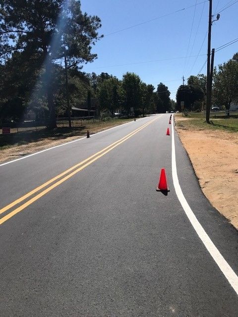 Empty road with orange cones marking a lane along a sunny suburban street