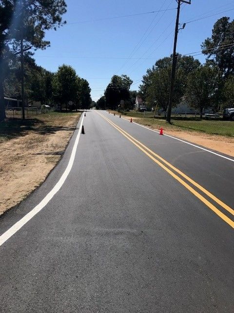 Empty two-lane road with double yellow lines and cones on the right under a clear sky
