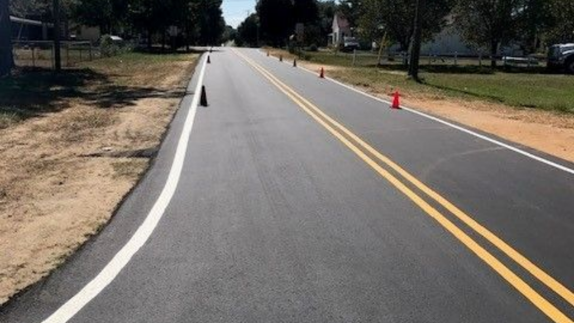 Empty paved road with double yellow lines and orange cones along the right side in Saint Pauls, NC