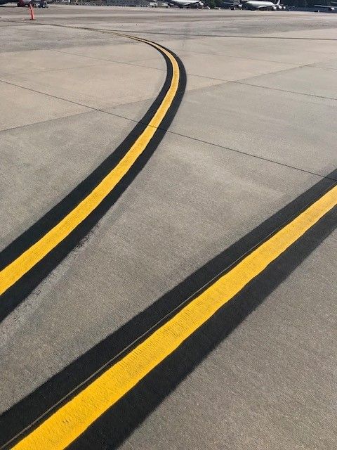 Yellow runway/taxiway lines curving across a concrete airport surface