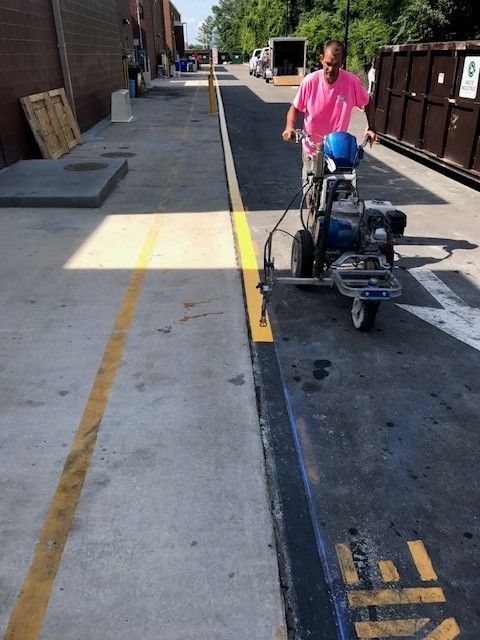 Person on a push floor-cleaning machine in an alley beside a building