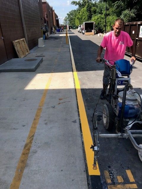 Man on a mobility scooter beside a yellow curb line on a sidewalk by a brick building.