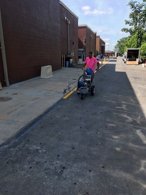 Person pushing a stroller along a wide sidewalk beside brick buildings on a sunny day