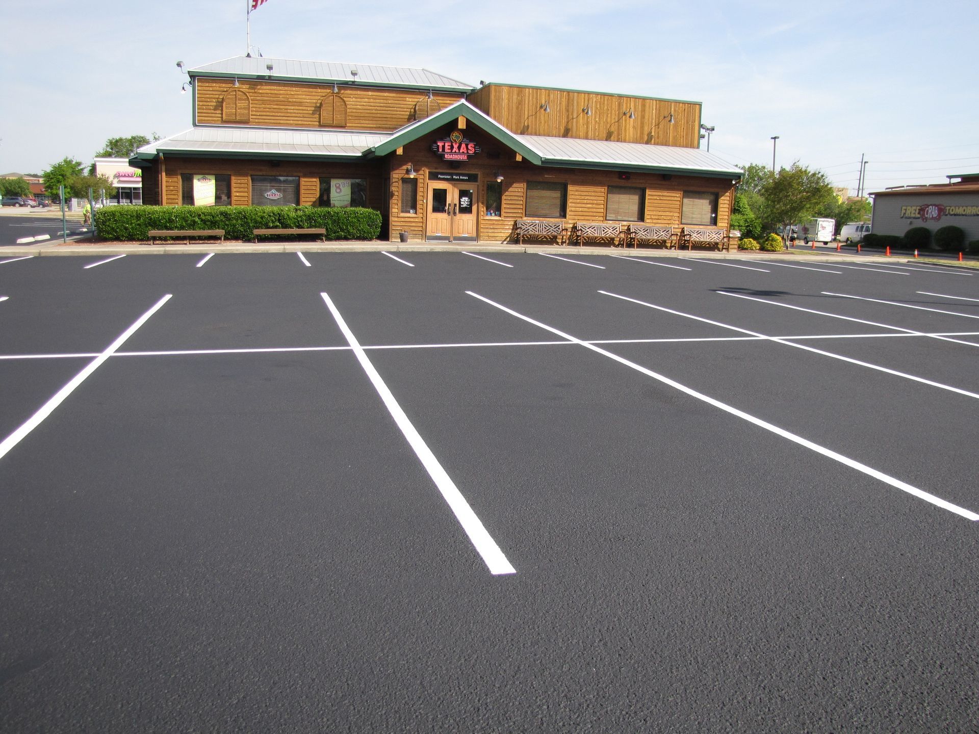 Empty parking lot in front of a tan building with a green-roofed entrance in Raleigh, NC