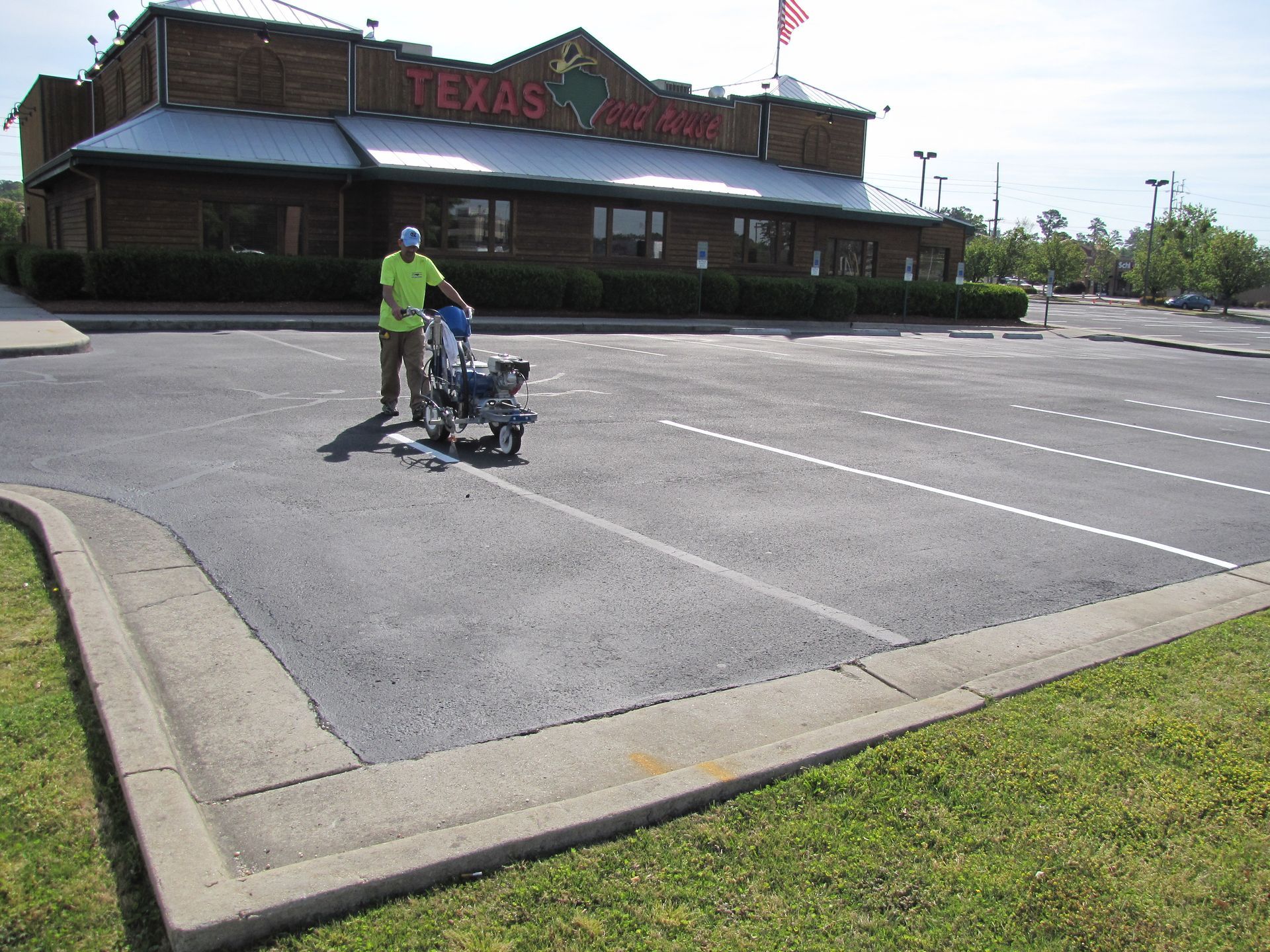 Person pushing a stroller in an empty parking lot outside a Texas-themed building