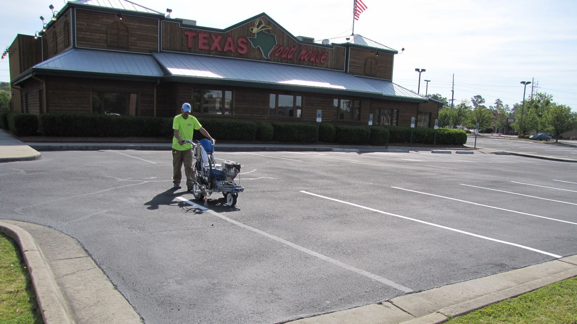 Worker pushing a cart in a nearly empty parking lot outside a texas roadhouse in Fayetteville, NC.