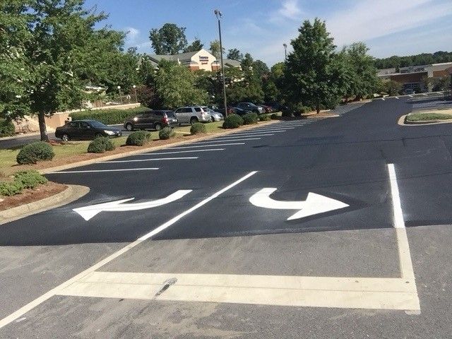 Parking lot lane with white directional arrows and trees along the side in Raleigh, NC