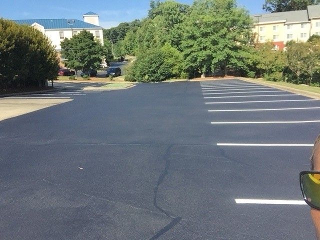 Empty parking lot with white painted spaces beside trees and buildings on a sunny day