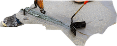 A worker uses a handheld tool to apply black sealant into a crack on a grey pavement surface.
