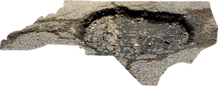 The shape of North Carolina cut out of asphalt, featuring a large, wet pothole in its center.