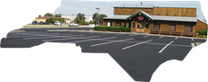 A wooden restaurant building with a large paved parking lot in front, cut out to resemble the shape of North Carolina.