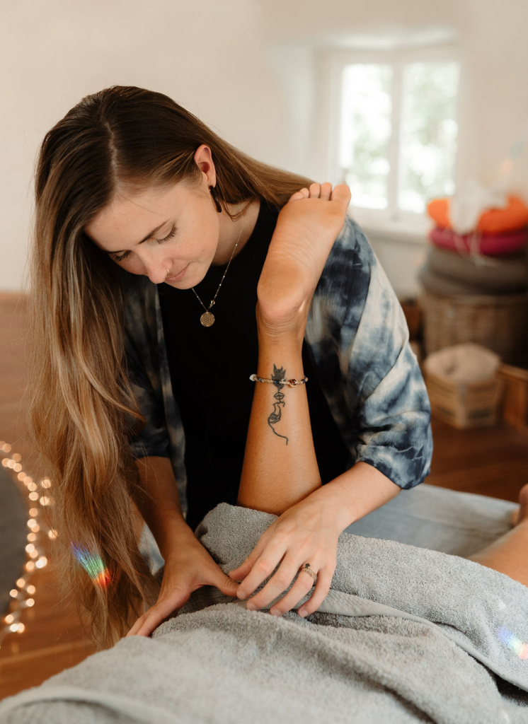 Woman performing massage on a leg, indoors. She is wearing a tie-dye shirt, with long hair, and is focused. — The Health Studio Sunshine Coast In Mooloolaba, QLD