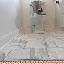 A bathroom with a toilet and a bucket on the floor.