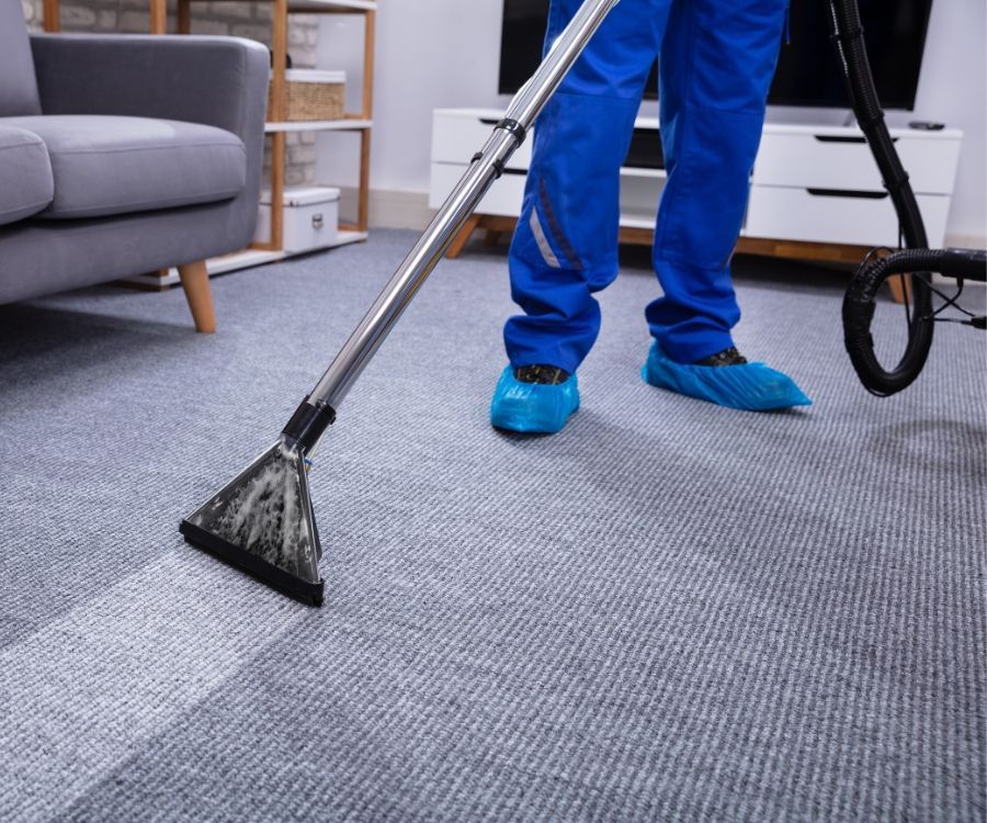 A person is using a vacuum cleaner to clean a carpet in a living room.