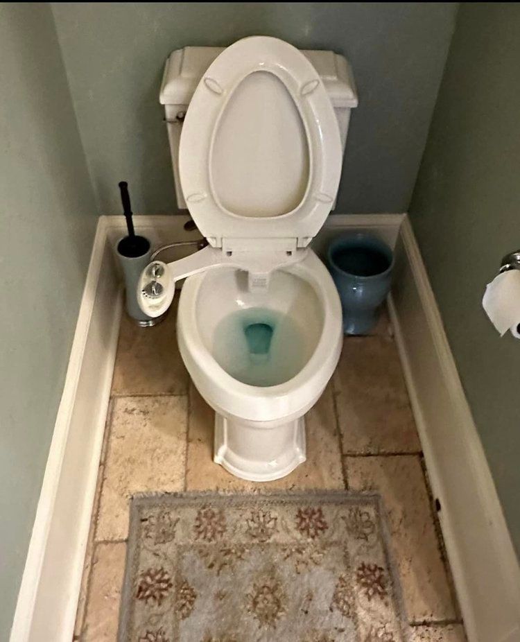 A toilet with a bidet attached to it in a bathroom
