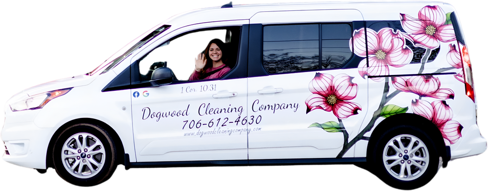 A woman is driving a white van with pink flowers on the side.
