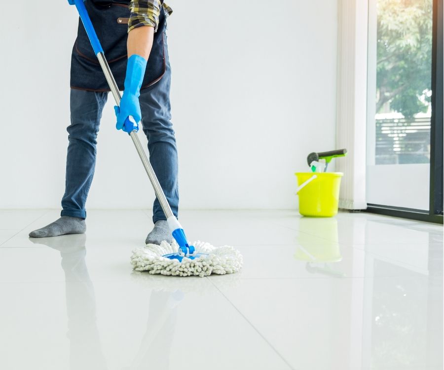 A man is cleaning the floor with a mop.