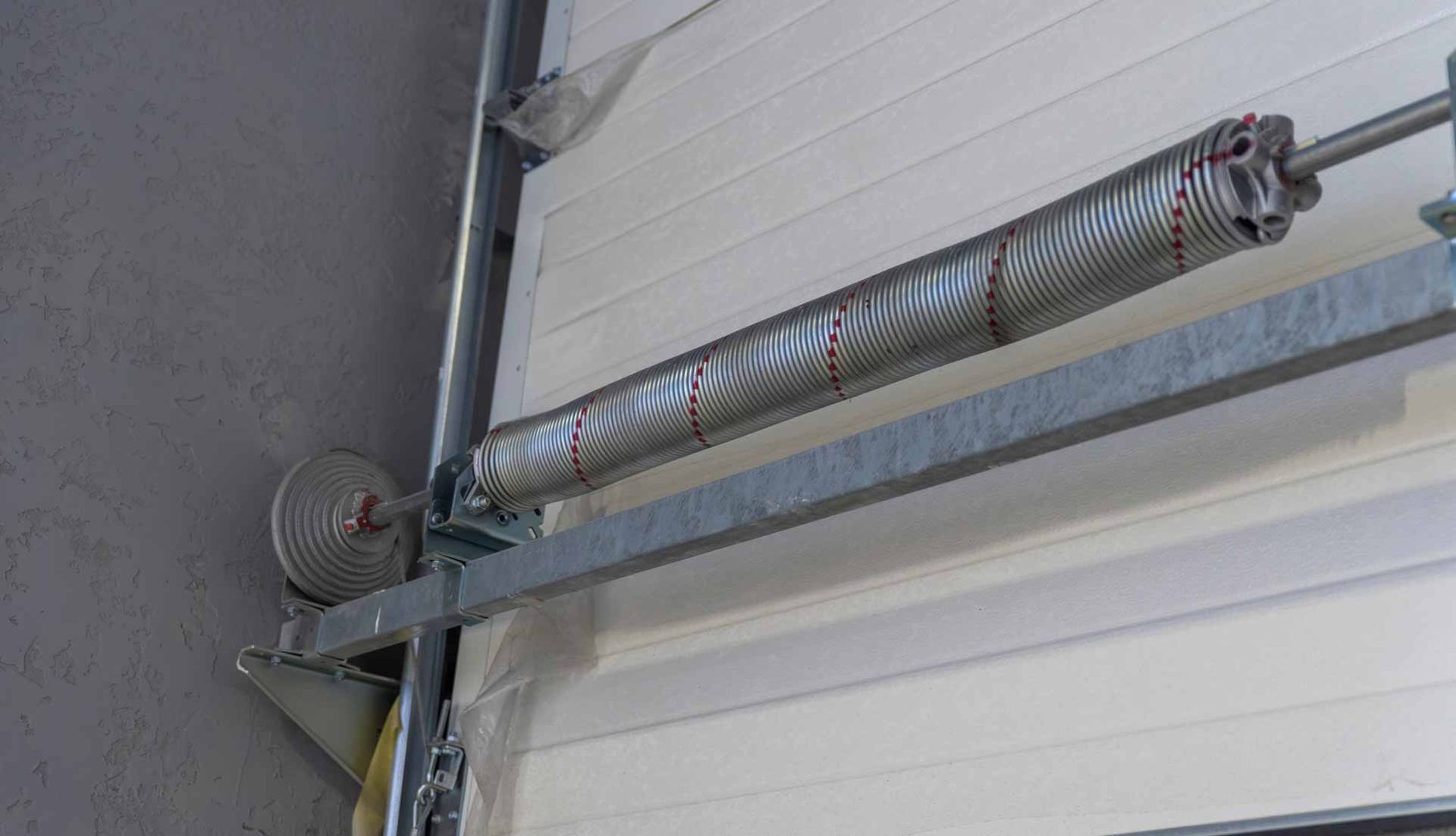 Garage door opener with a metal rail, motor, and coiled spring mounted near the ceiling