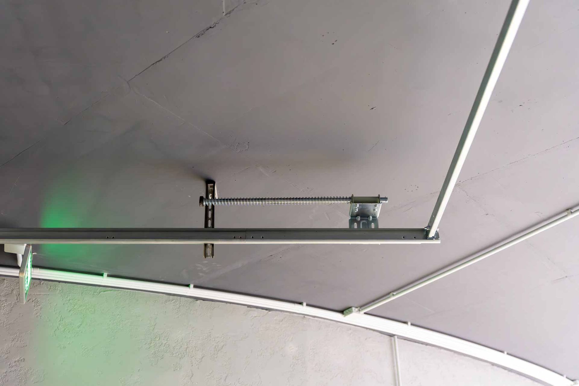 Ceiling-mounted garage door track and spring mechanism in a white room
