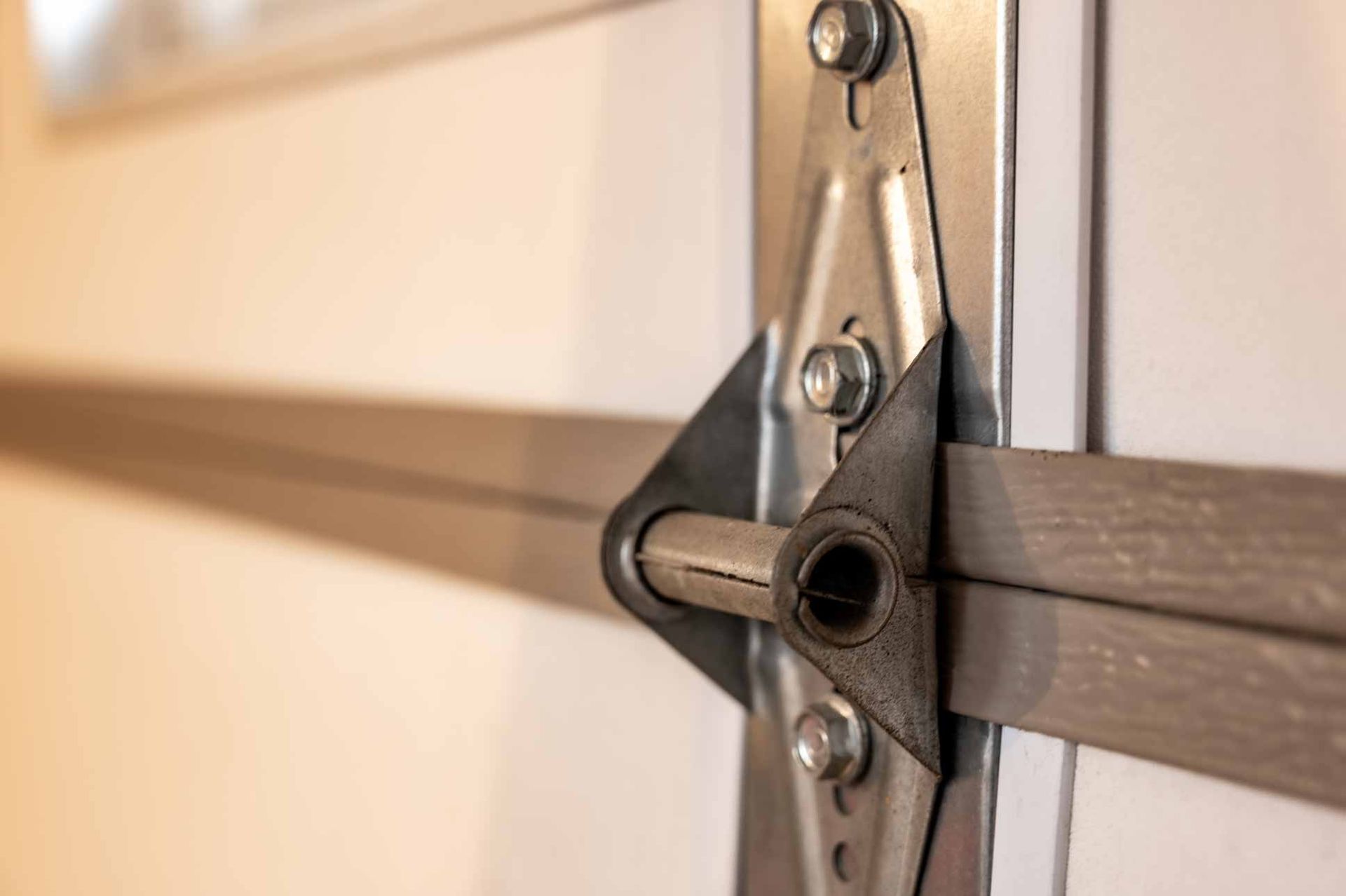 Close-up of a garage door hinge and metal support arm on a beige door panel