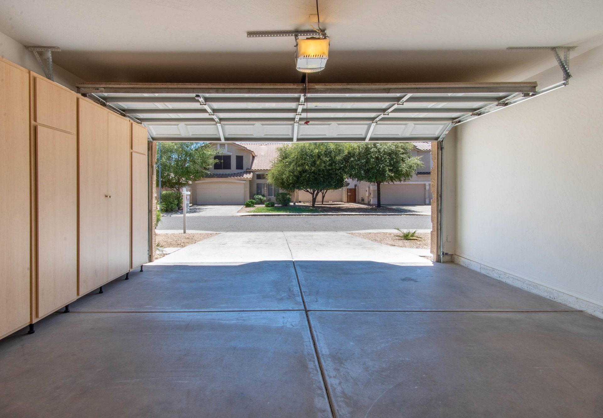 Empty garage with open door, concrete floor, and street view outside