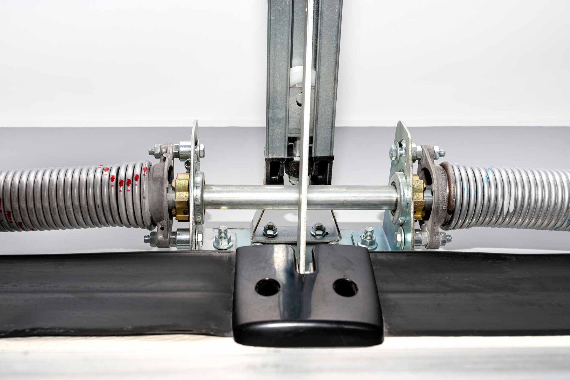 Close-up of a metal spring-loaded mechanism with black handles on a white background