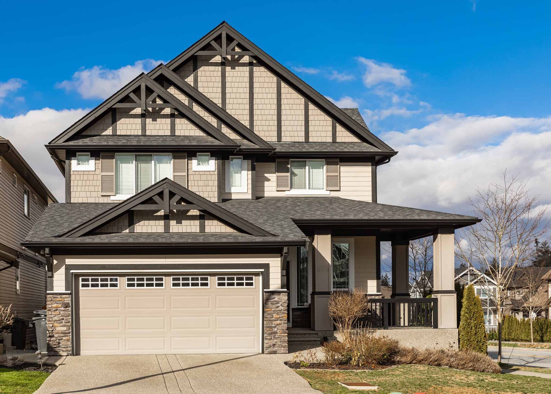 Two-story gray house with a front garage and covered porch under a blue sky