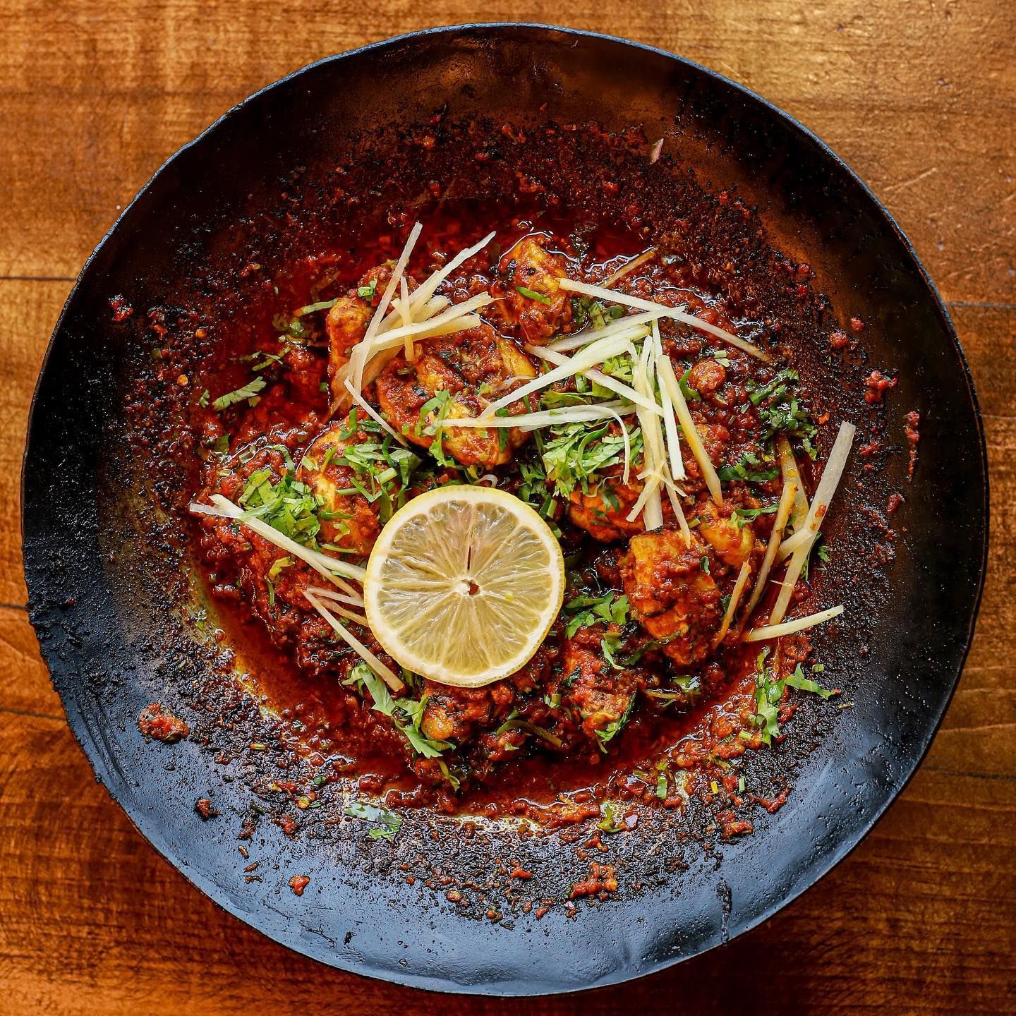 A plate of food with a lemon slice on top of it on a wooden table.