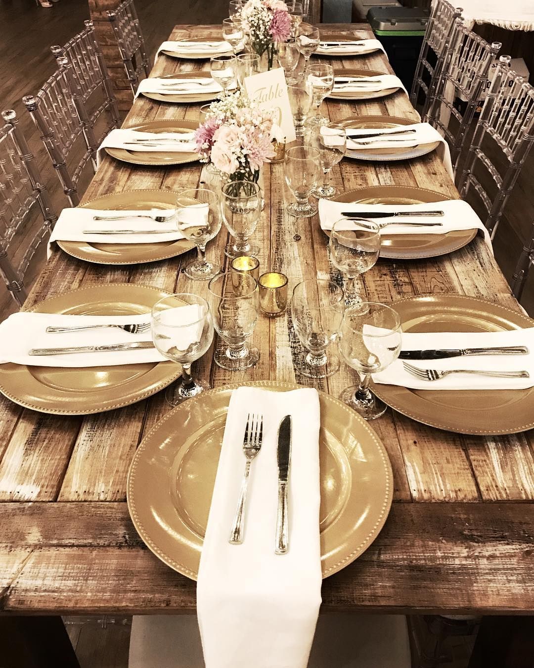 A long wooden table with plates , silverware , and candles on it.