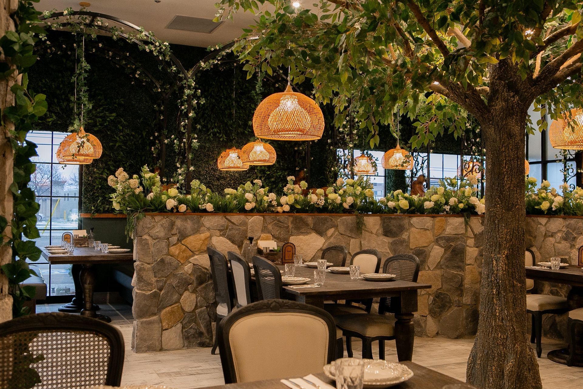 A restaurant with tables and chairs and a tree in the middle of the room.