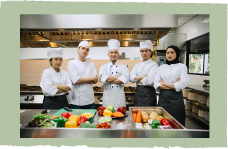 A group of chefs are standing in a kitchen with their arms crossed.