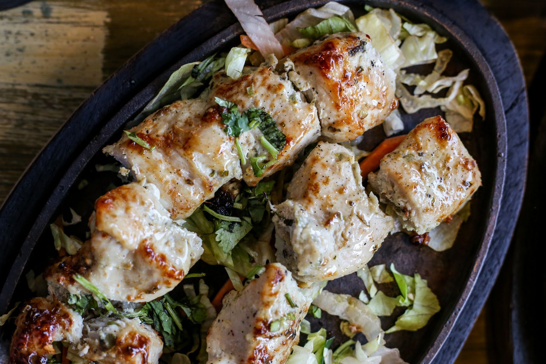 A close up of a plate of food with meat and vegetables on a table.