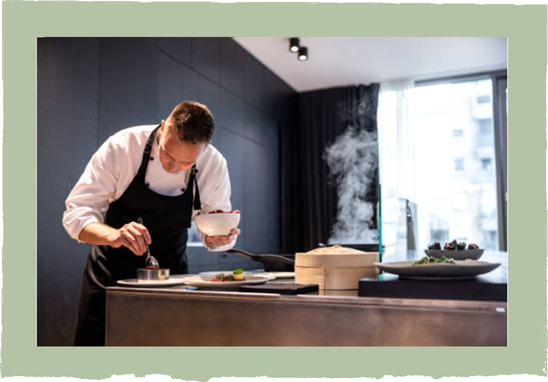 A man in an apron is preparing food in a kitchen.