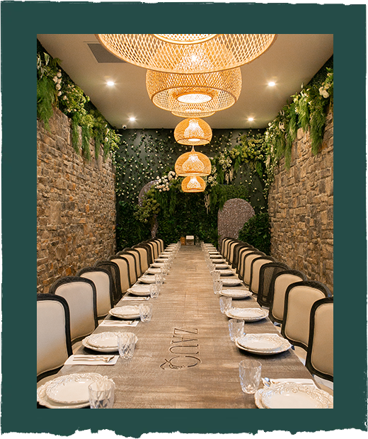 A long table with plates and glasses in a room with a brick wall.