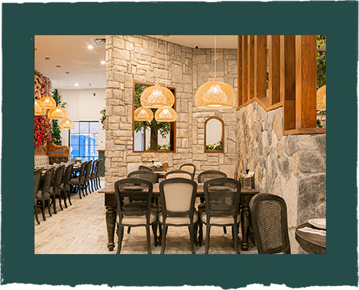 A restaurant with tables and chairs and a stone wall.