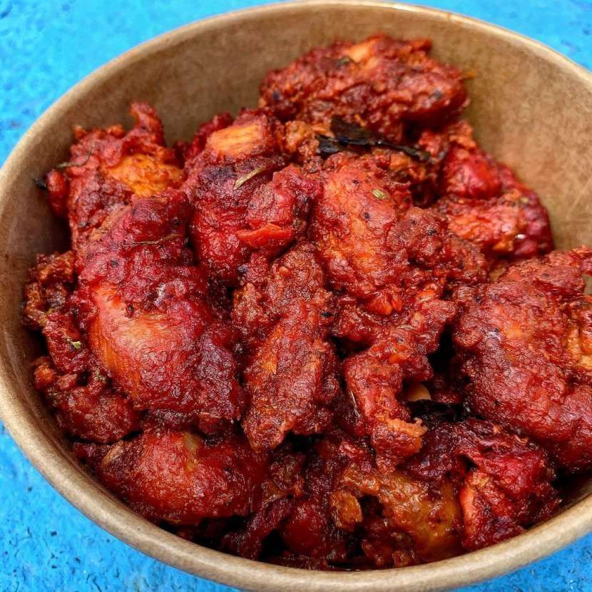 A bowl of fried chicken on a blue surface.