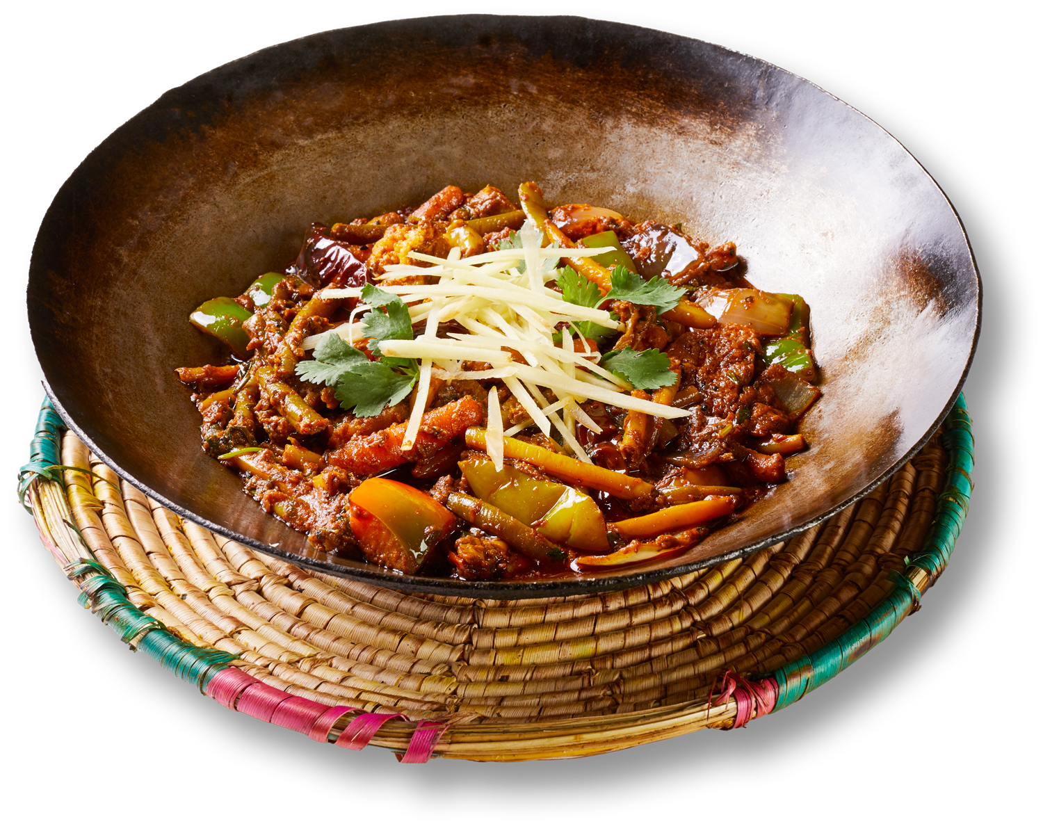 A wok filled with meat and vegetables on a wicker mat